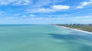 Eine Küstenansicht mit blauem Himmel, Sandstrand und einer Reihe von Gebäuden entlang der Küste.