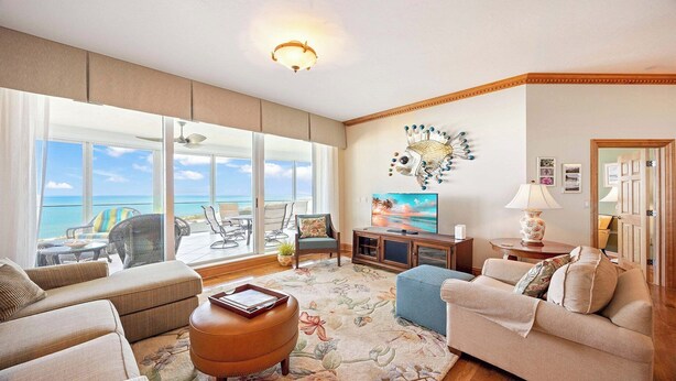 Ein großzügiges Wohnzimmer mit großem Fenster zum Meer, einem Fernseher und einem Wanddekor.