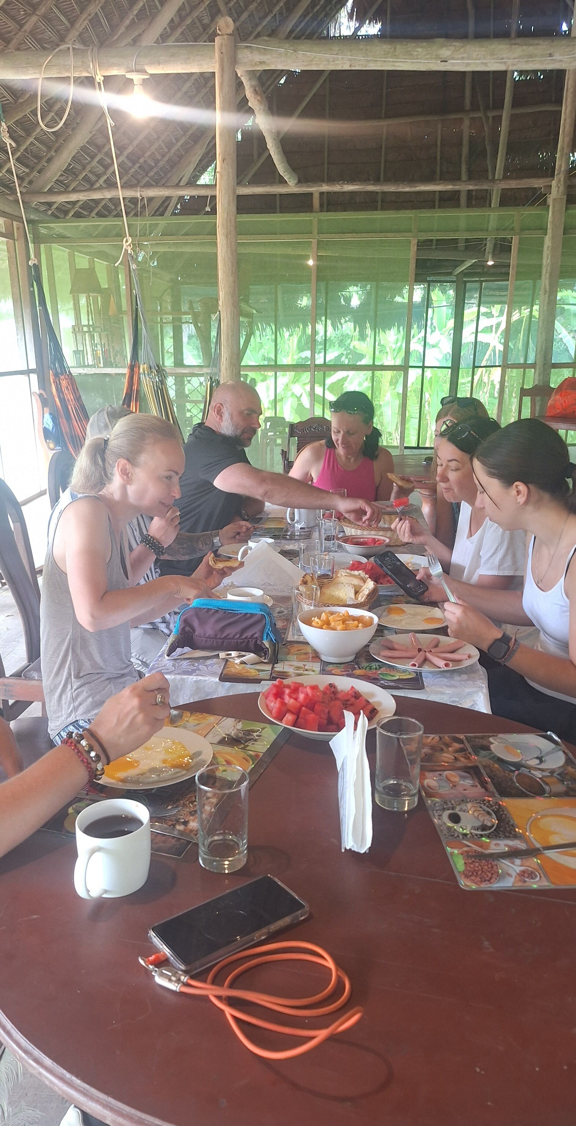 A group of people dining at a table with various dishes, a mobile phone, and a cup.