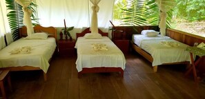 Quarto com três camas de madeira, cada uma com roupa de cama branca e um dossel.