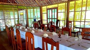 A dining area with tables set for multiple people, chairs, and a water dispenser.