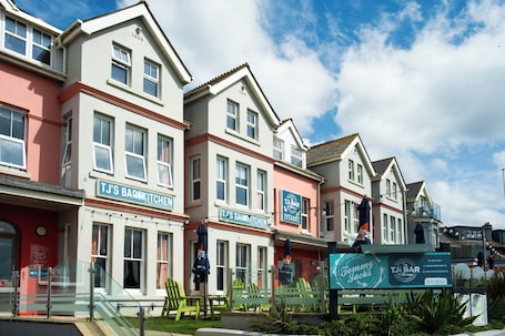 A row of buildings with signage for 'TJ's Bar & Kitchen' and 'TJ's Bar & Kitchen Entrance.'. Family King Room with Attached Single Room