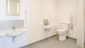 Un baño moderno con lavamanos, inodoro y bidé, todo en color blanco.