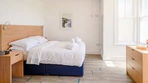 Un dormitorio moderno con cama, mesita de noche y ventana.
