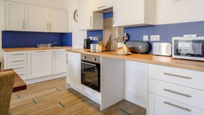 Una cocina moderna con armarios blancos, encimera de madera, horno empotrado y microondas.