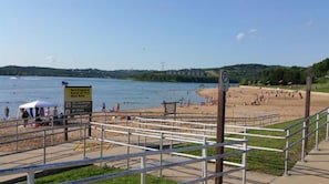 Ein Strand mit einer Rettungsschwimmer-Schild, einem Schild mit der Aufschrift 'Schwimmen auf eigene Gefahr' und einem Schild, das den Konsum alkoholischer Getränke verbietet.