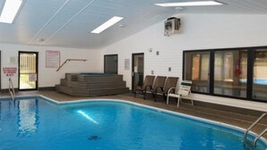 En inomhuspool med klart vatten, ett takfönster och en säkerhetsskylt.