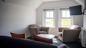 Una habitación con dos ventanas, un televisor de pantalla plana y un sofá.