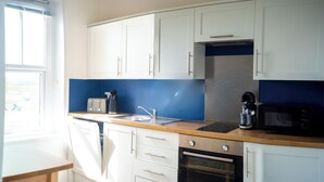 Een keuken met witte kasten, een blauwe achterwand, een broodrooster, een koffiezetapparaat en een magnetron.