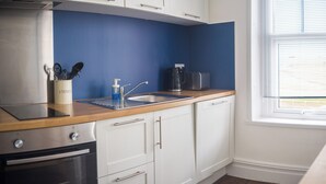 Una cucina con un piano di lavoro in legno, un lavello in acciaio inossidabile, una macchina da caffè e un tostapane.