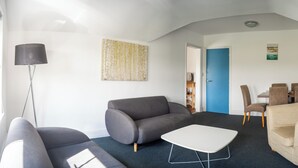 Ein modernes Wohnzimmer mit einer Couch, einem Couchtisch, einer Lampe und einem Essbereich mit Stühlen und einem Tisch.
