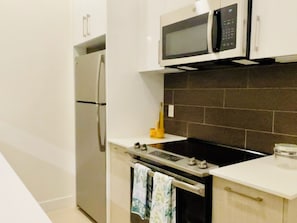 Cuina moderna amb nevera, microones, forn i una petita zona de rentat.