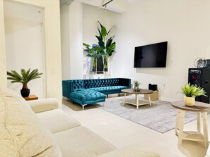 Un saló modern amb un sofà modular, un televisor de pantalla plana, una taula de centre i plantes en testos.