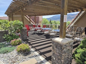 Une terrasse extérieure avec des tables et des chaises, une pergola et un panneau indiquant un espace barbecue propre.