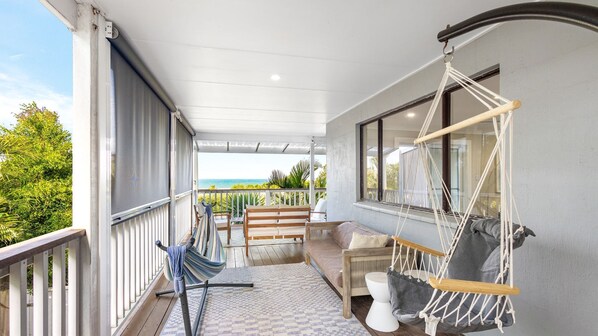 Ein Balkon mit einer Hängematte, einer Sitzecke und Blick auf das Meer.