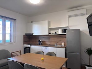 Eine kleine Küche mit Holztischplatte, eingebautem Backofen, Spüle und Kühlschrank.