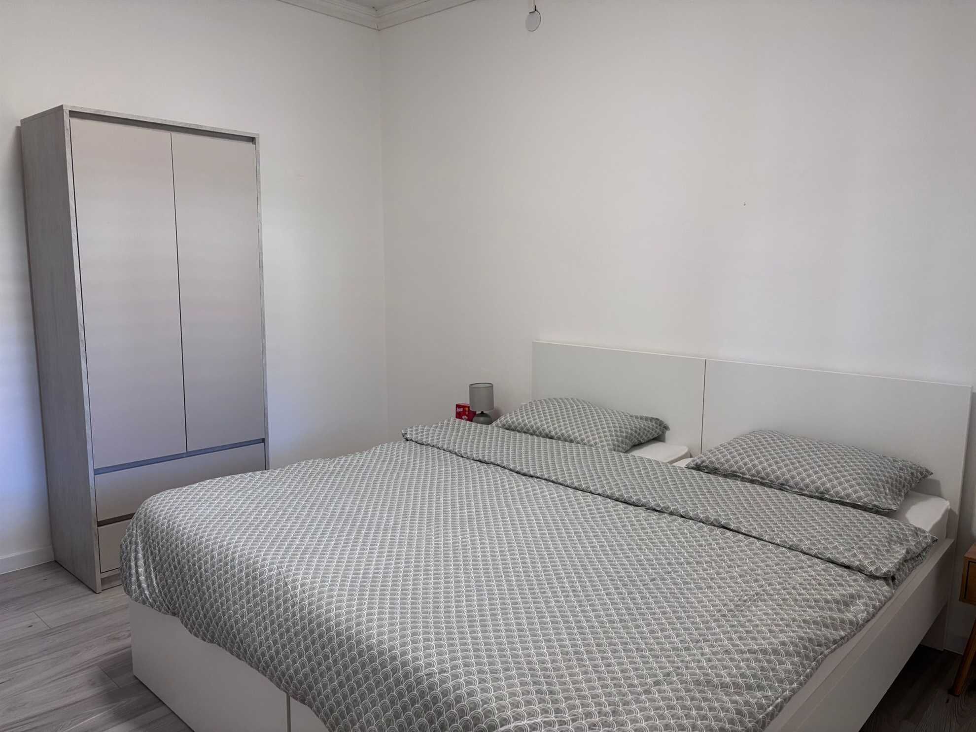 Ein Schlafzimmer mit einem Bett, einem Kleiderschrank und einem Nachttisch.