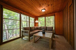 Eine Holzhütte mit großen Fenstern, einer Couch und einem Tisch.