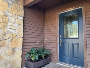 Ein Haus mit Steinaußenwand, einer blauen Tür und einem Blumentopf mit Pflanzen.