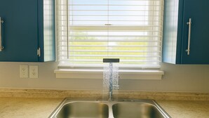 A kitchen with a double sink, a window with blinds, and a countertop. - LuxModern Sparkling Clean 3BR 2BA by Ft. Hood-King Bed-MassageChair-PetFriendly! (Copperas Cove)