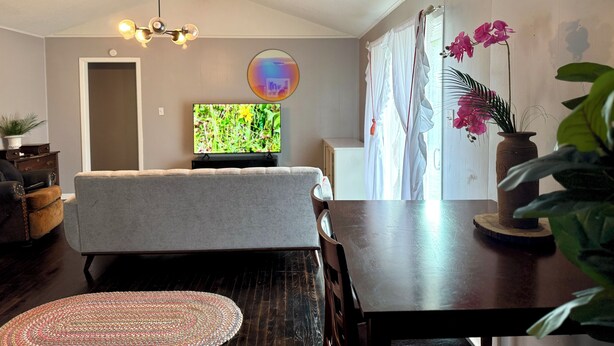 A living room with a sofa, a TV, a wooden ceiling, a dining table, and a potted plant. - LuxModern Sparkling Clean 3BR 2BA by Ft. Hood-King Bed-MassageChair-PetFriendly! (Copperas Cove)