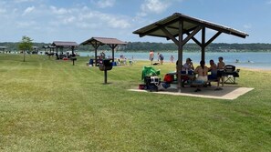 Eine Wiese mit Picknicktischen und einem See im Hintergrund.