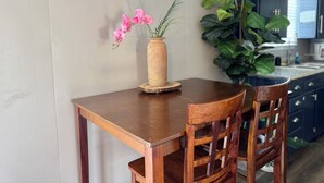 A wooden dining table with a vase of pink flowers and a large green plant. - LuxModern Sparkling Clean 3BR 2BA by Ft. Hood-King Bed-MassageChair-PetFriendly! (Copperas Cove)