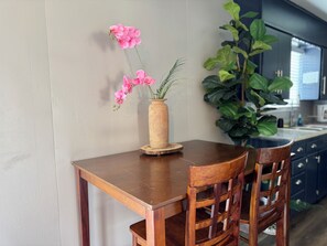 A wooden dining table with a vase of pink flowers and a large green plant. - LuxModern Sparkling Clean 3BR 2BA by Ft. Hood-King Bed-MassageChair-PetFriendly! (Copperas Cove)