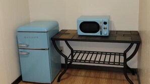 A small kitchenette with a blue refrigerator, a microwave, and a black metal table. - Crescent Motel (Crescent)