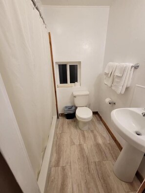 Ett badrum med toalett, fönster, handfat och handdukshängare.