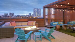 A rooftop terrace with a sofa, chairs, a fire pit, and a view of the city skyline. - Downtown Nashville Studio – Margaritaville Pool & Live Music (Nashville)