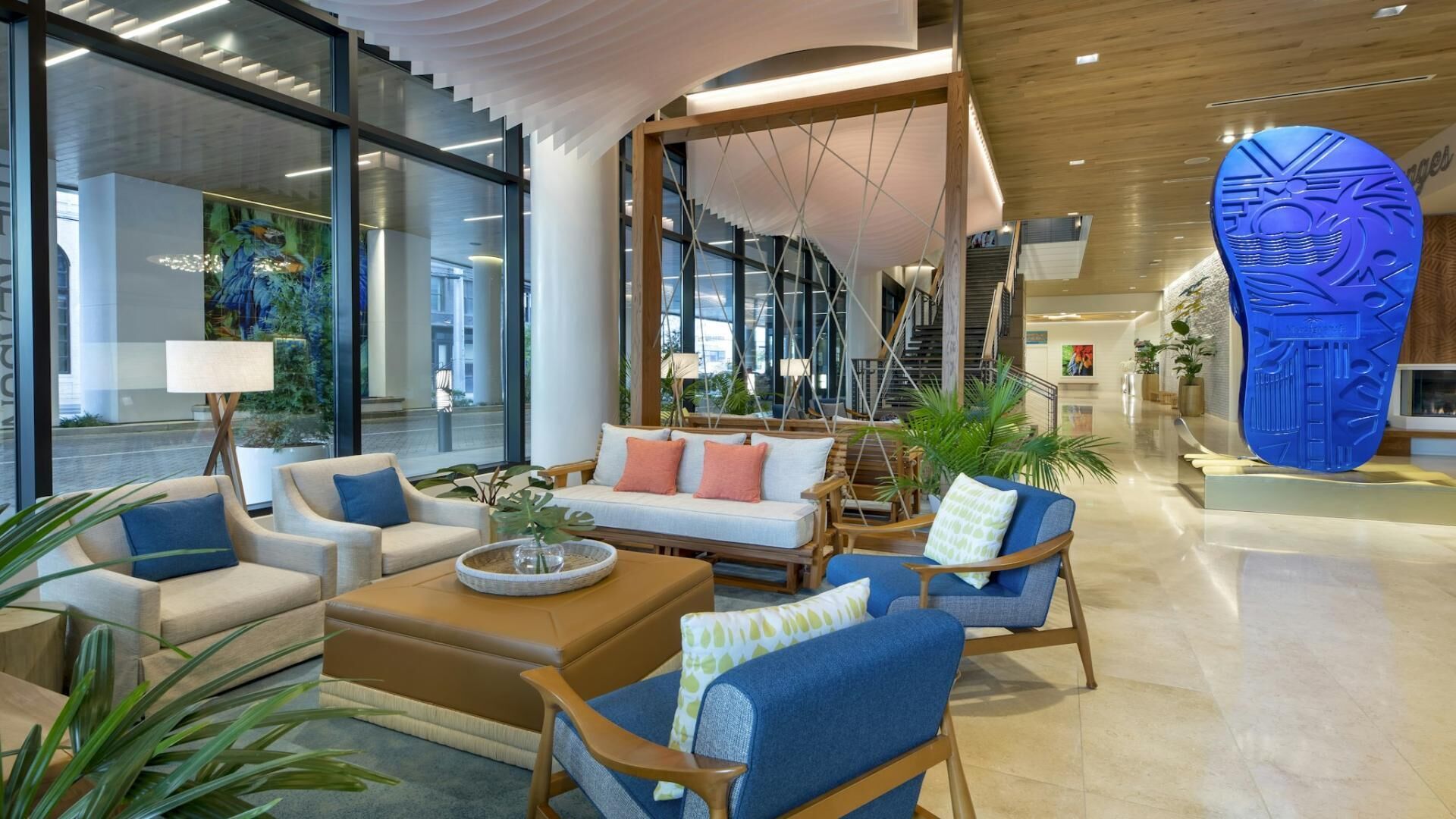 A modern lobby with seating areas, a staircase, and a large blue sculpture.