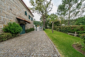 A stone building with a cobblestone pathway leading to a green lawn and a gate.