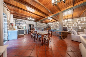A spacious dining area with a wooden table and chairs, a stone wall, and a pool table.