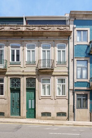 Un edifici d'edificis amb una porta verda, diverses finestres i balcons.