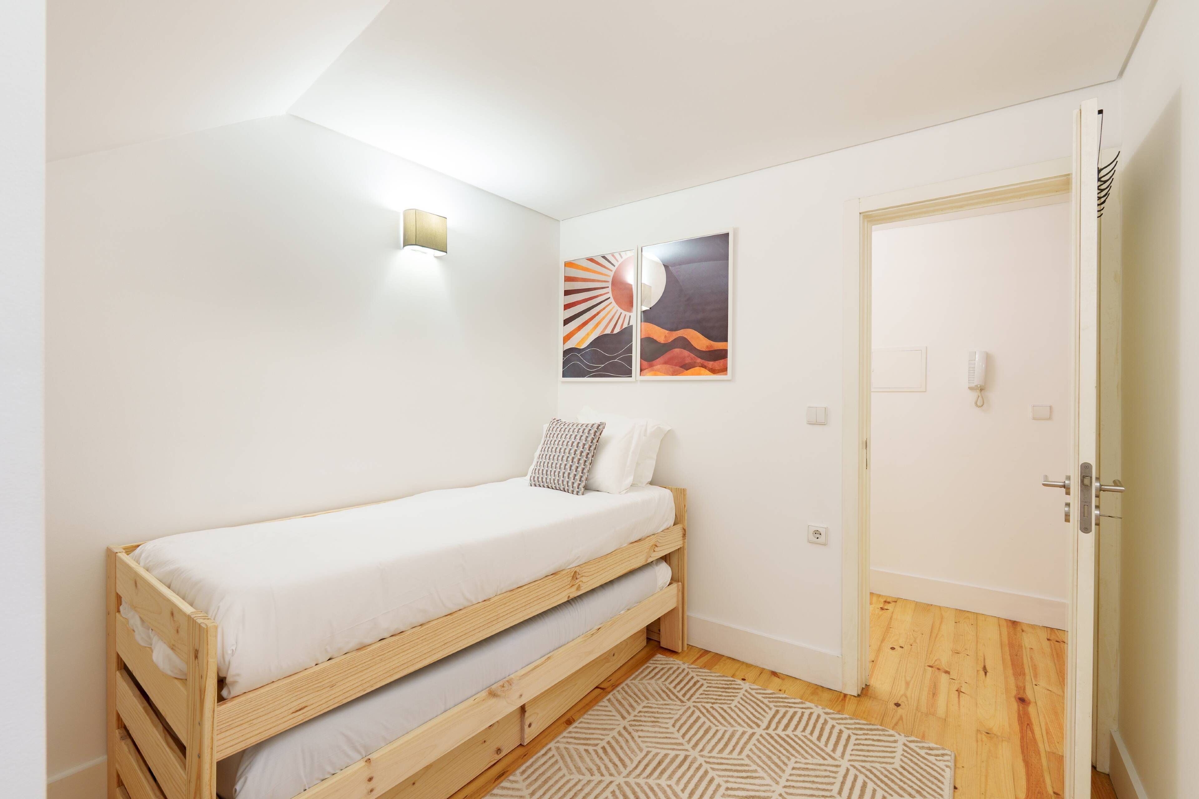 Ett litet, rent rum med en våningssäng, en vägglampa och två inramade tavlor.