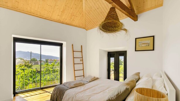 Quarto com uma janela grande, uma cama, uma escada e uma porta que dá para o exterior.