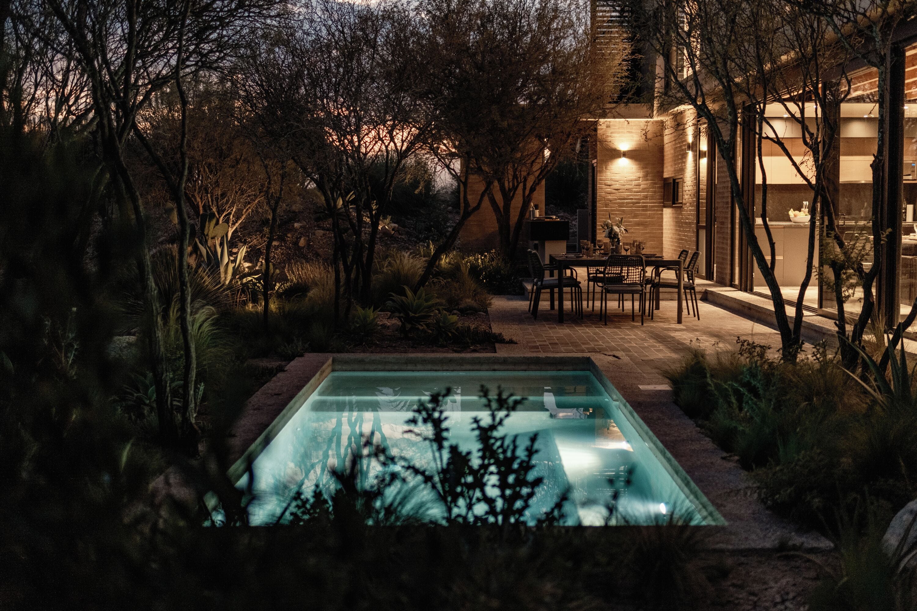 A pool surrounded by trees and a building with a brick exterior.