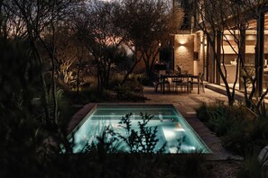 A pool surrounded by trees and a building with a brick exterior.