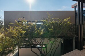A modern building with a flat facade, large windows, and a tree in the foreground.