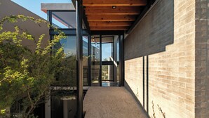 A modern building with a glass facade, a wooden ceiling, and a gravel pathway. -  Casa Iremia by VIATO HOMES (San Miguel de Allende)