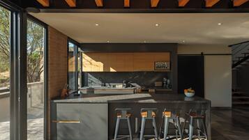 Una cocina moderna con una isla central, taburetes de bar y vistas al exterior.