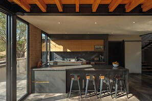 A modern kitchen with a central island, bar stools, and a view of the outdoors. -  Casa Iremia by VIATO HOMES (San Miguel de Allende)