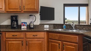 Una cocina con armarios de madera, cafetera, licuadora y ventana con vistas.
