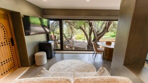 A modern interior with a large window, a round seating area, a wooden door, and a flat-screen TV. - Olive Tree House - Paderne, Albufeira (Albufeira)