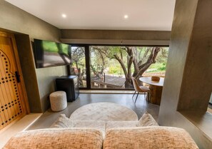 A modern interior with a large window, a round seating area, a wooden door, and a flat-screen TV. - Olive Tree House - Paderne, Albufeira (Albufeira)