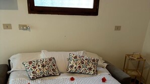 En pænt redt seng med blomsterpuder, sammenrullet håndklæder og røde blomster.