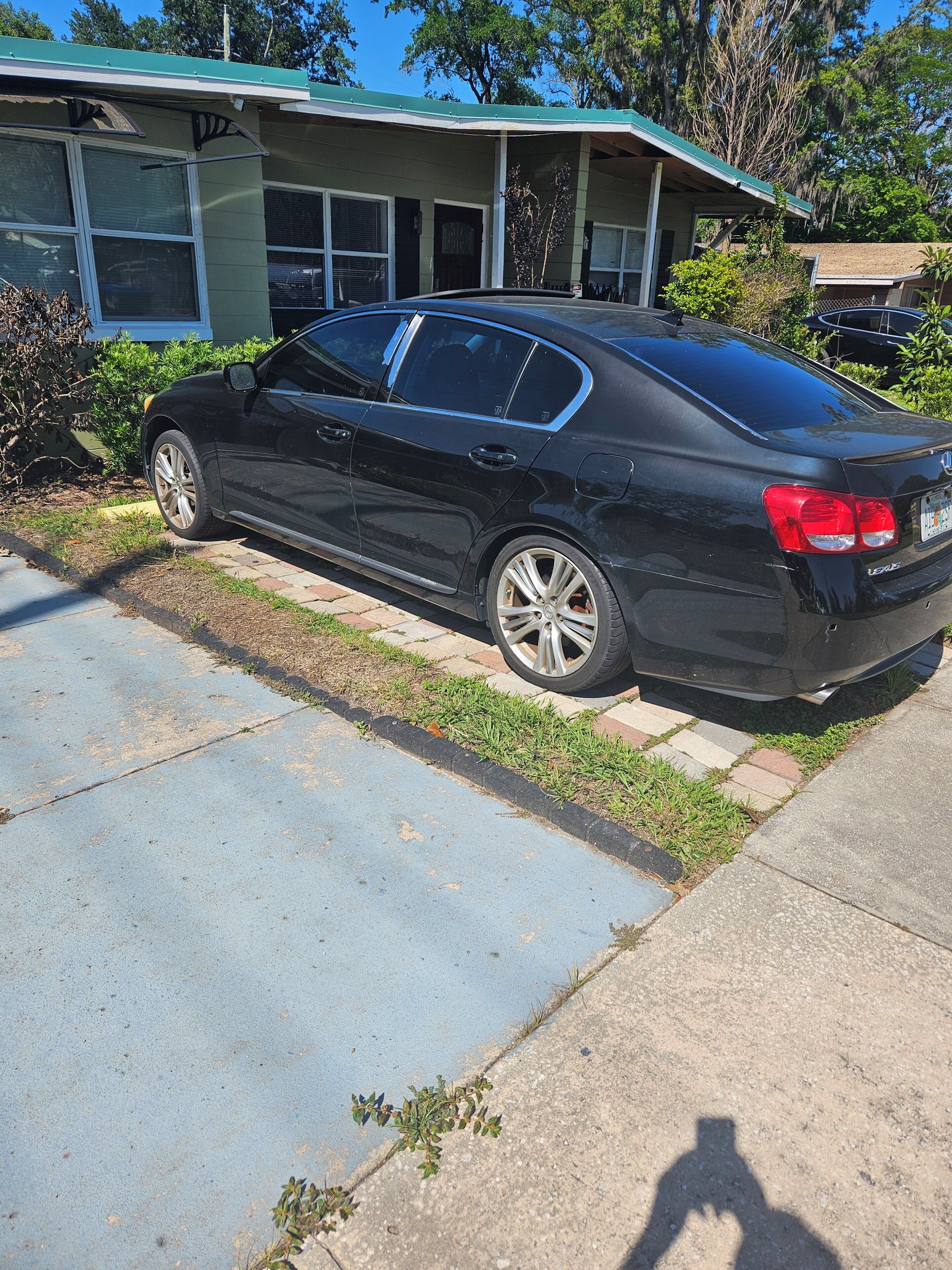 Um sedan preto estacionado em frente a um edifício com telhado verde e grandes janelas.