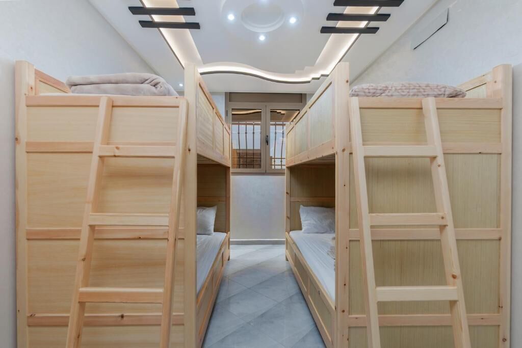 A bunk bed room with a ladder, a small window, and a ceiling light fixture.