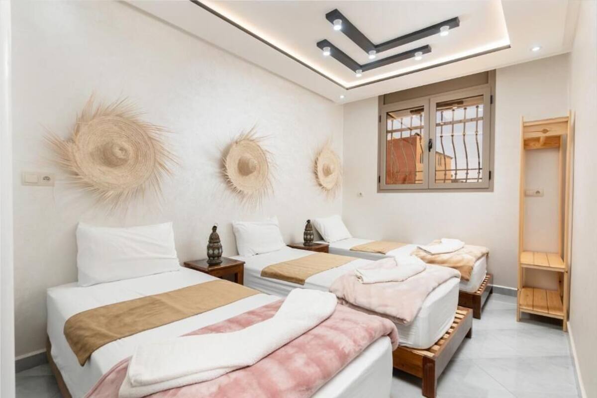 Habitació d'hotel moderna amb tres llits, un armari de fusta i un gran finestral amb vistes.